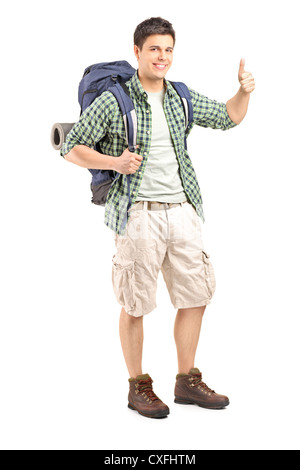 Full length portrait of a male hiker with backpack giving a thumb up isolated on white background