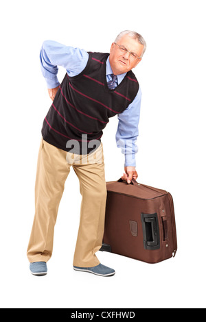 Full length portrait of a senior man lifting his luggage and suffering from a back pain isolated on white background Stock Photo