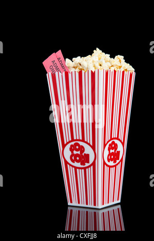 red and white container with movie theater popcorn and movie tickets on a black background Stock Photo