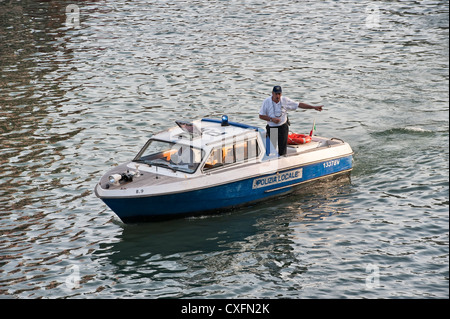A member of the polizia locale (local police) directing boat traffic on the Grand Canal in Venice, Italy Stock Photo