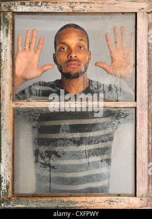 African American man looking out old grunge window Stock Photo