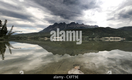 Yellowhead Lake British Columbia with the mountains and sky reflected therein and a freight train on the far side Stock Photo