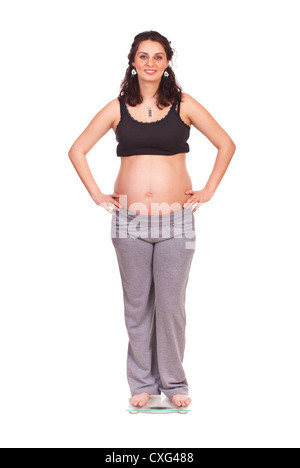 Smiling pregnant woman on weight scale isolated on white background Stock Photo