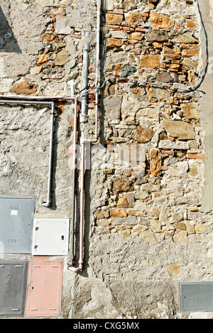 Plumbing and electrical construction on a outside wall, Castellina Marittima Tuscany Italy Stock Photo