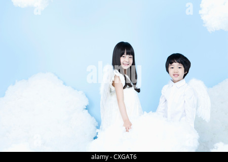 two kids with looks of angels on the clouds Stock Photo