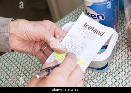 Elderly woman checking prices of shopping looking at till receipt bill Stock Photo