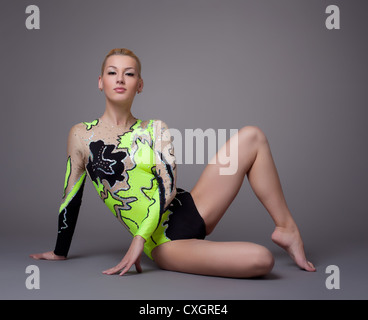 Young woman in gymnast suit posing on grey Stock Photo