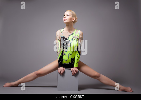 Cute professional gymnast doing a splits on cube Stock Photo