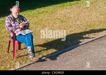 Man reading book outside on grass - France. Stock Photo
