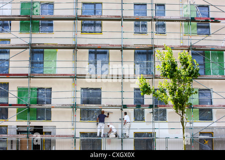 Worker on a scaffolding, plastering the wall of a new apartment building. Stock Photo