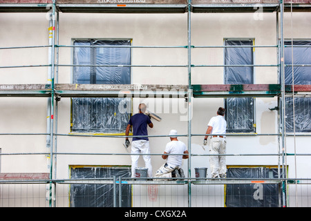 Worker on a scaffolding, plastering the wall of a new apartment building. Stock Photo
