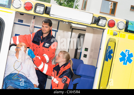 Paramedics checking IV drip patient in ambulance treatment aid emergency Stock Photo