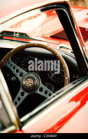 Detail of red E-Type Jaguar showing steering wheel, badge and instruments Stock Photo