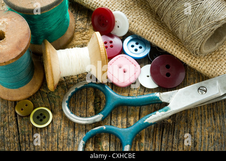 Spools of threads and buttons on old wooden table Stock Photo