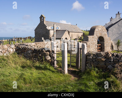 Isle of Anglesey Coast Path signpost and kissing gate by tiny 5th century church of St Patrick. Llanbadrig Cemaes Anglesey Wales UK Stock Photo
