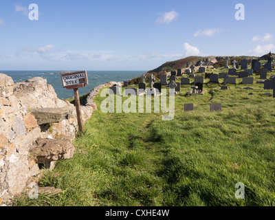 Original old stone stile with sign on churchyard wall around St Patrick's church on Isle of Anglesey Coastal Path at Llanbadrig. Stock Photo