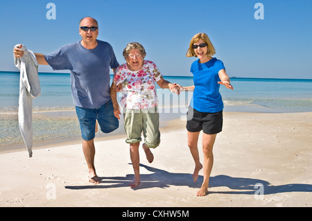 Three adults having fun on a beach, one elderly and two middle aged. Stock Photo