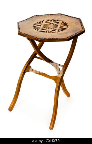 Vintage folding three-legged wooden coffee / side table with carved top Stock Photo