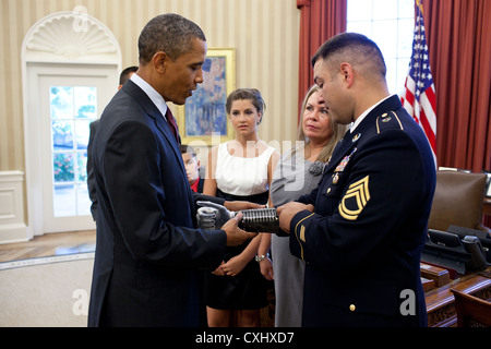 US Army Sergeant First Class Leroy Petry shows President Barack Obama a plaque with the names of the fallen Rangers from the 75th Regiment on his prosthetic arm during a meeting July 12, 2011 in the Oval Office of the White House. The President later awarded SFC Petry the Medal of Honor for his courageous actions during combat operations against an armed enemy in Paktya, Afghanistan in May 2008. Stock Photo