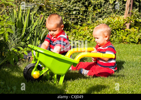 Two little brothers playing in the garden during sunny day. Stock Photo