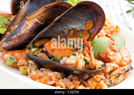 Seafood Paella with mussels, shrimps and calmari as closeup in a white plate Stock Photo