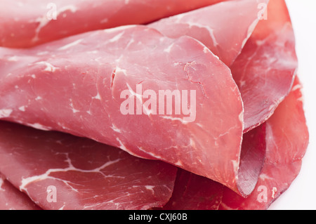 Pressed meat slices rolled as closeup on a white plate Stock Photo