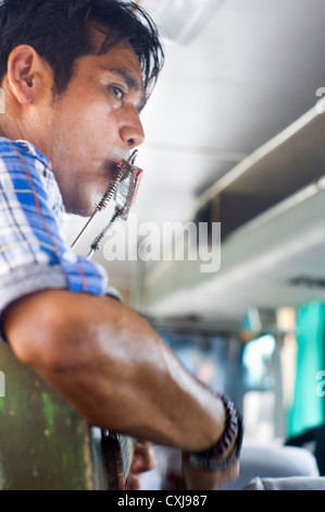 An indonesian man busking by singing in the bus, asia scene. Slight motion shakes are visible at 100% zoom. Stock Photo