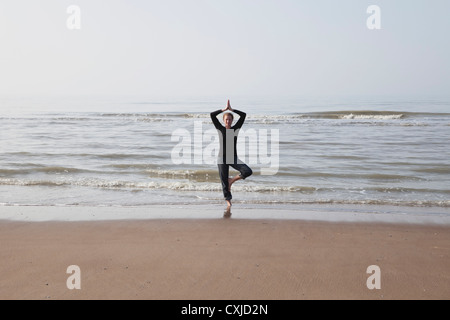 Belgium, Young woman exercising at North Sea Stock Photo