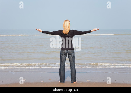 Belgium, Young woman meditating at North Sea Stock Photo