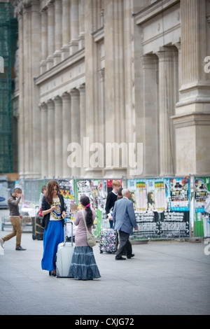 A Romani gypsy outside SNCF Paris Gare du Nord railway station in France, holds a hand-written card to a pretty mature lady Stock Photo