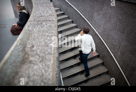 Young man talking on his mobile phone walking up steps from a pedestrian walkway in Paris France Stock Photo