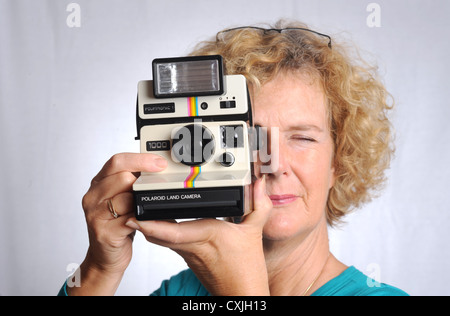 Female woman with an old Polaroid Land Camera 1000 UK Stock Photo