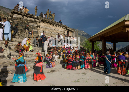 Kalash women and girls overlooked by security forces at the Grum Village Charso (dancing ground), Kalash Joshi (Spring Festival), Rumbur Valley, Chitral, Khyber-Pakhtunkhwa, Pakistan Stock Photo