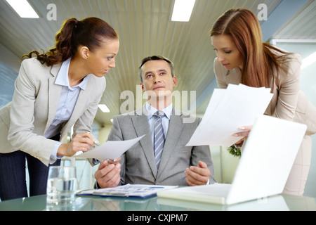 Inspirated boss sitting at workplace surrounded by two secretaries Stock Photo