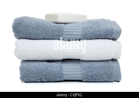 Stack of gray and white towels and a bar of soap on a white background Stock Photo
