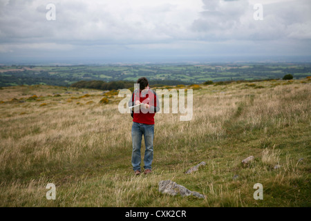 Man map reading in a field, Dartmoor National Park, UK Stock Photo