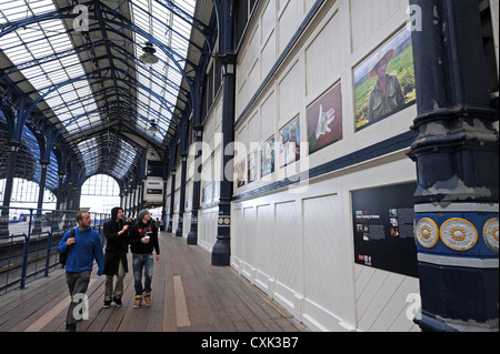 Commuters looking at an exhibition of Photographs by Lulu Ash depicting food production around the world at Brighton station Stock Photo