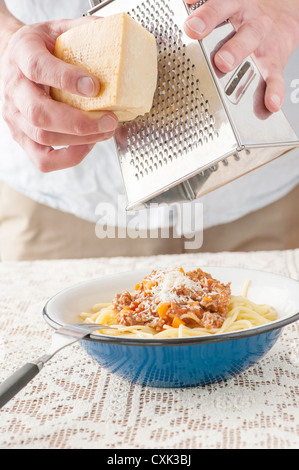 Serving of pasta bolognaise. The chef is adding grated parmesan cheese on top. Stock Photo