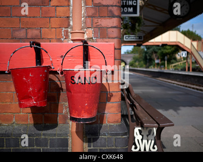 Red fire buckets. Vintage emergency sand filled fire buckets at Toddington Historic train station Nr. Broadway Gloucestershire England UK Stock Photo