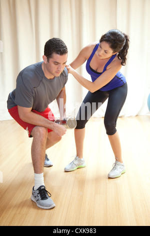 A man is working out with a female personal trainer. Stock Photo