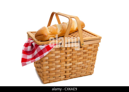 A wicker picnic basket with a loaf of French bread and a red gingham ...
