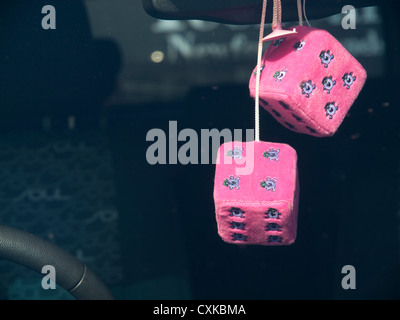 Furry dice hanging from the rear mirror in a car. Stock Photo