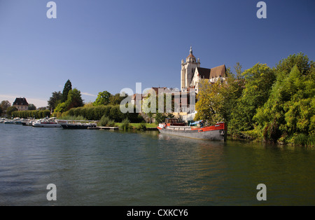 French church on riverside in Dole, with boats and barges on a bright Summer's day. Stock Photo