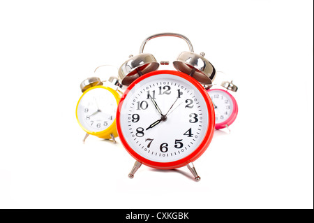 Several brightly colored traditional alarm clocks thrown on a white background Stock Photo
