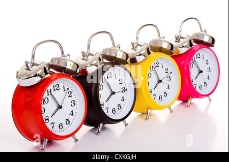 Several brightly colored traditional alarm clocks thrown on a white background Stock Photo