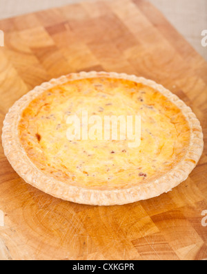 Fresh baked quiche lorraine on a wooden chopping board Stock Photo