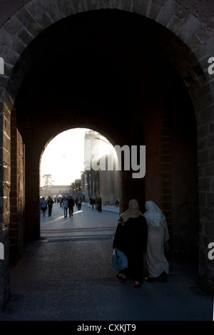 Two Moroccan women walking through arch, Essaouira, Morocco Stock Photo