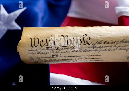 A copy of the United States of America Constitution scroll in front of a large American Flag, focus is on the word people. Stock Photo