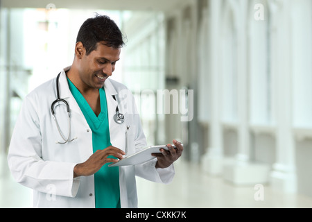 Male Indian doctor holding a digital tablet & standing in a hospital. Stock Photo
