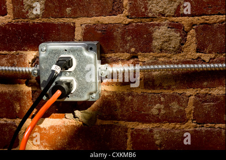 Electrical plug on a brick wall with a cord or extension cord plugged in, concept of connecting or power Stock Photo